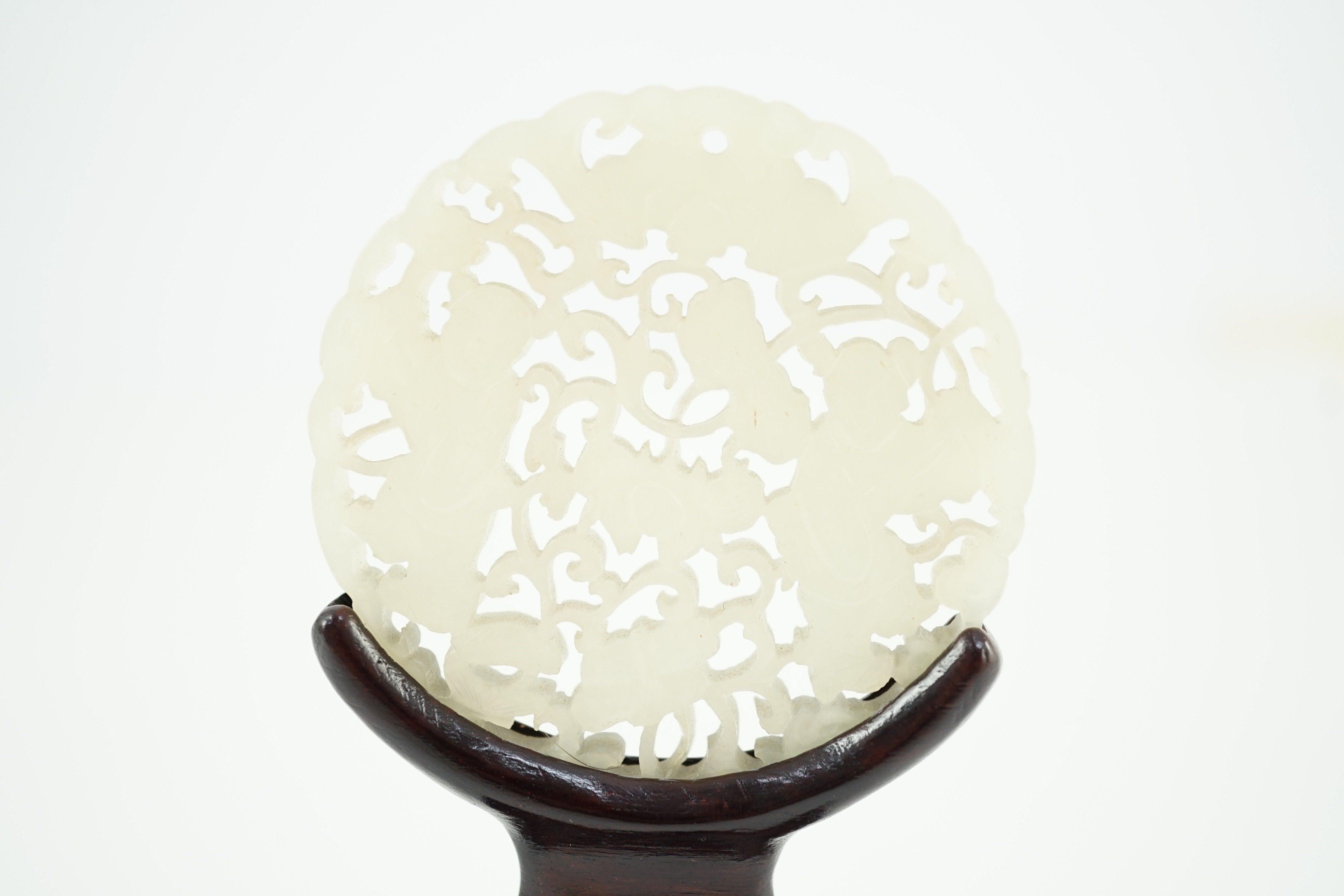 A Chinese white jade ‘Hehe Erxian’ disc, 19th/20th century, 5.6cm diameter, wood stand